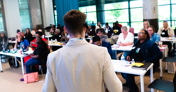 Man in front of a classroom, speaking to a diverse classroom of adults