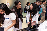One woman looking off screen as two women behind her look at a prototype on a table in a crowded Ross Winter Garden